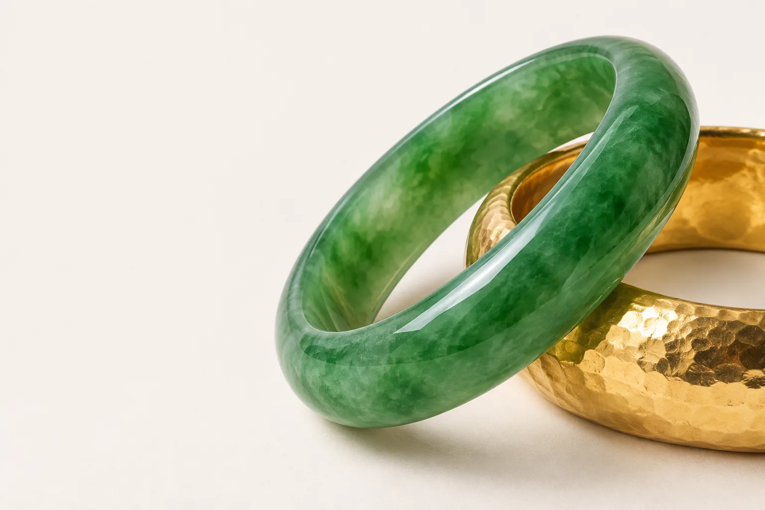 An imperial green jadeite bangle resting against a hammered 24-karat gold bangle